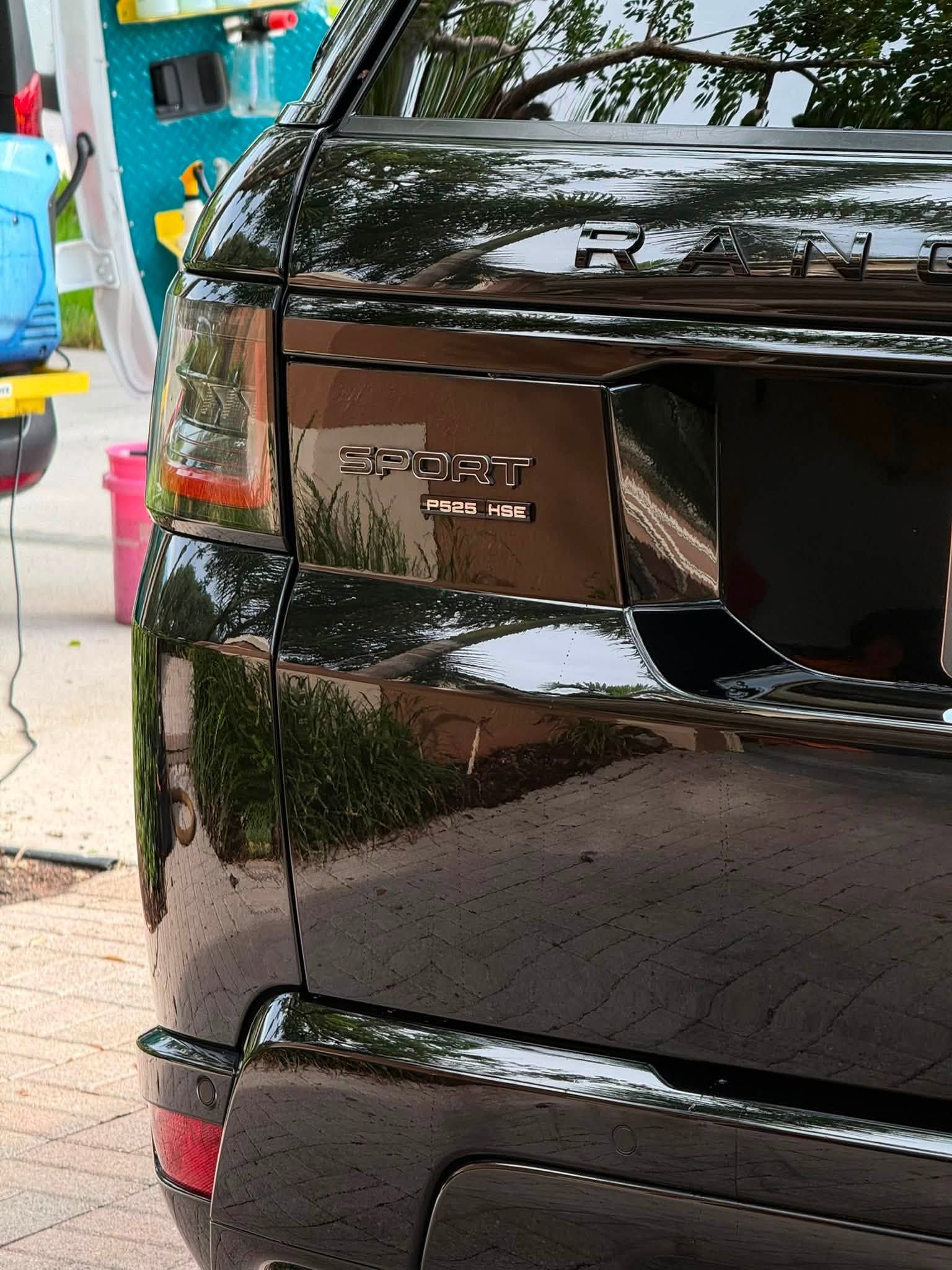 Rear of a black car with damaged taillight and an open trunk