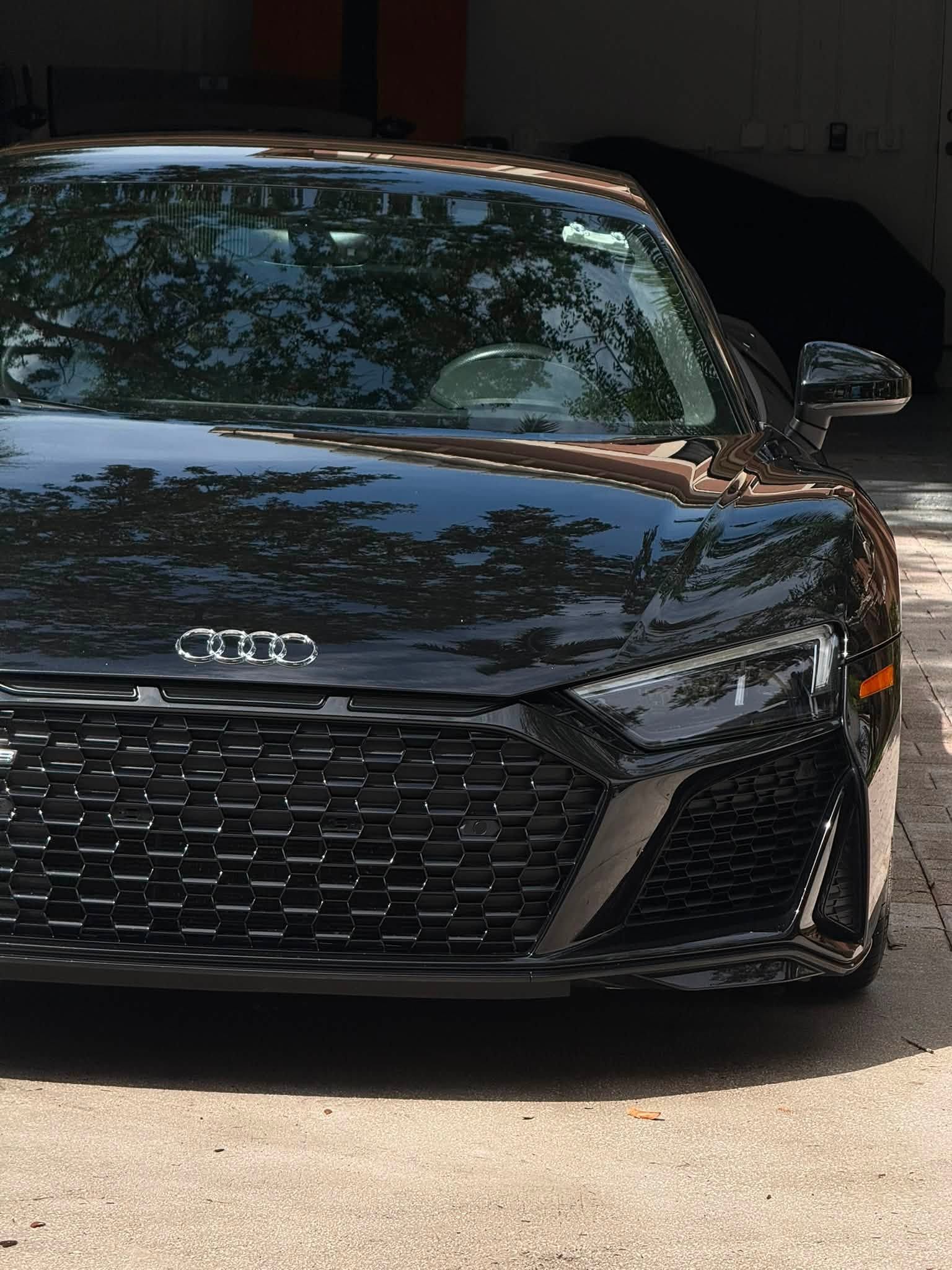 Front view of a black Audi sports car parked in a garage entrance