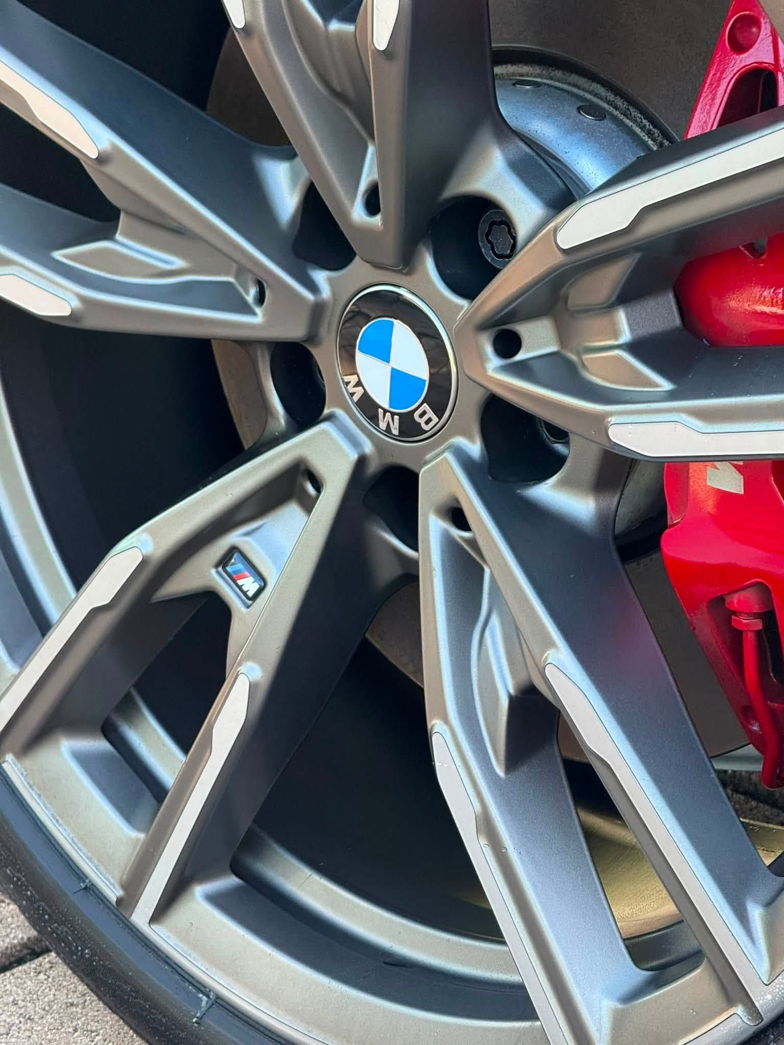 Close-up of a BMW alloy wheel with silver spokes and a red brake caliper