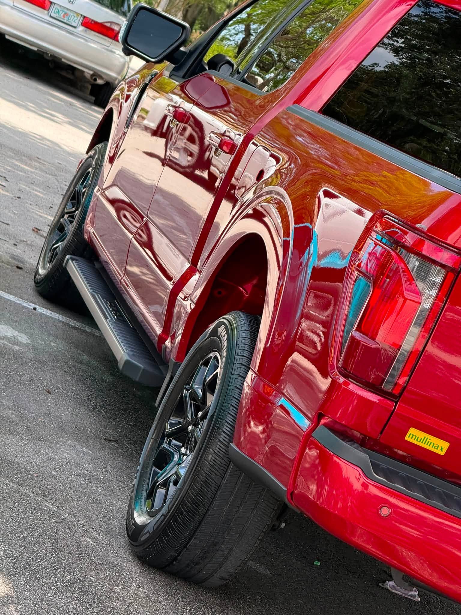 Red pickup truck parked at an angle on a road, with glossy maroon paint and black wheels.