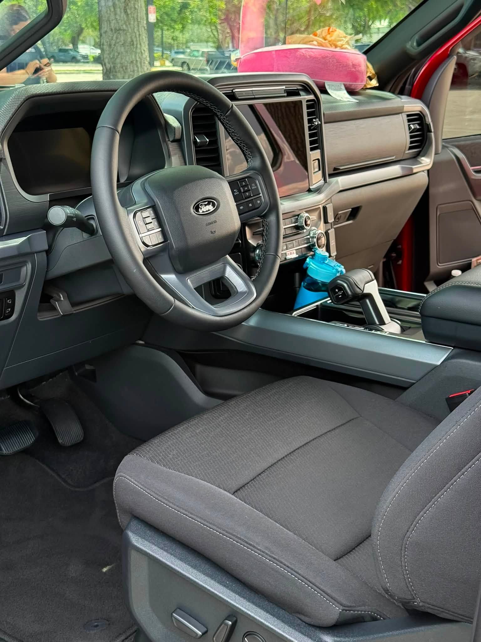 Ford truck interior with black seats, steering wheel, and center console, viewed from the driver’s side