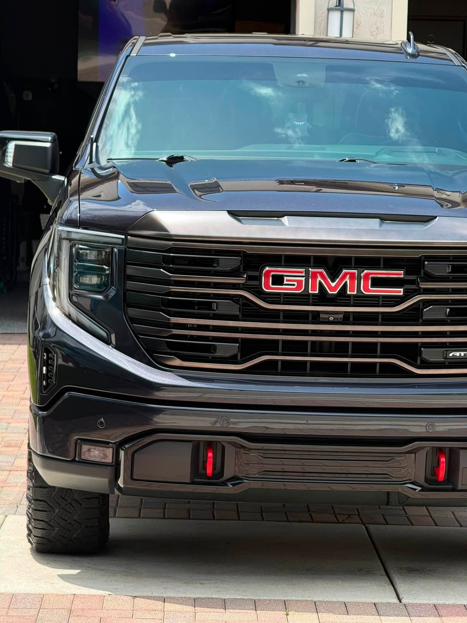 Black GMC pickup truck front view parked on a driveway, with red accents on the grille.