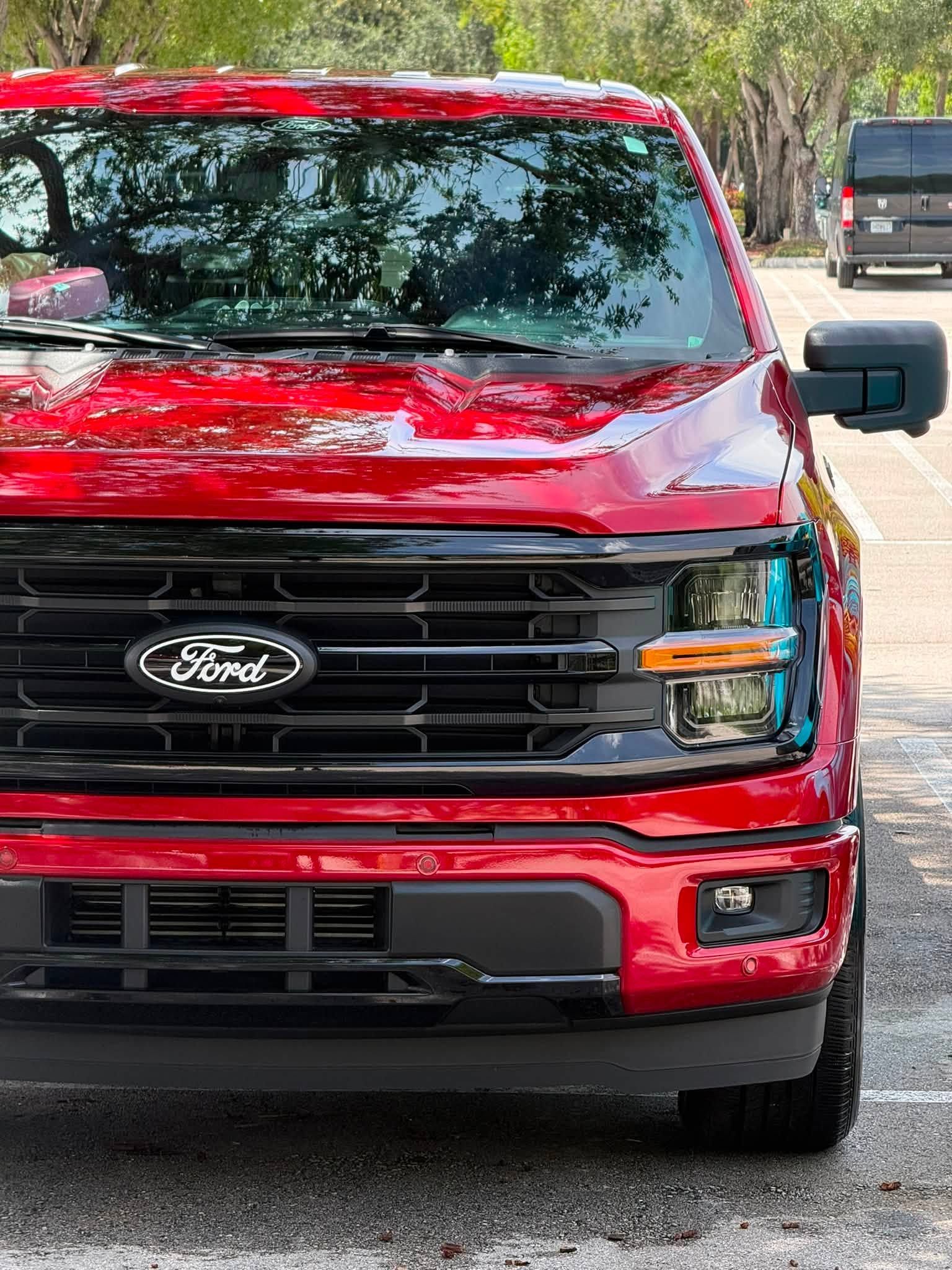 Red Ford pickup truck parked outdoors on a tree-lined road