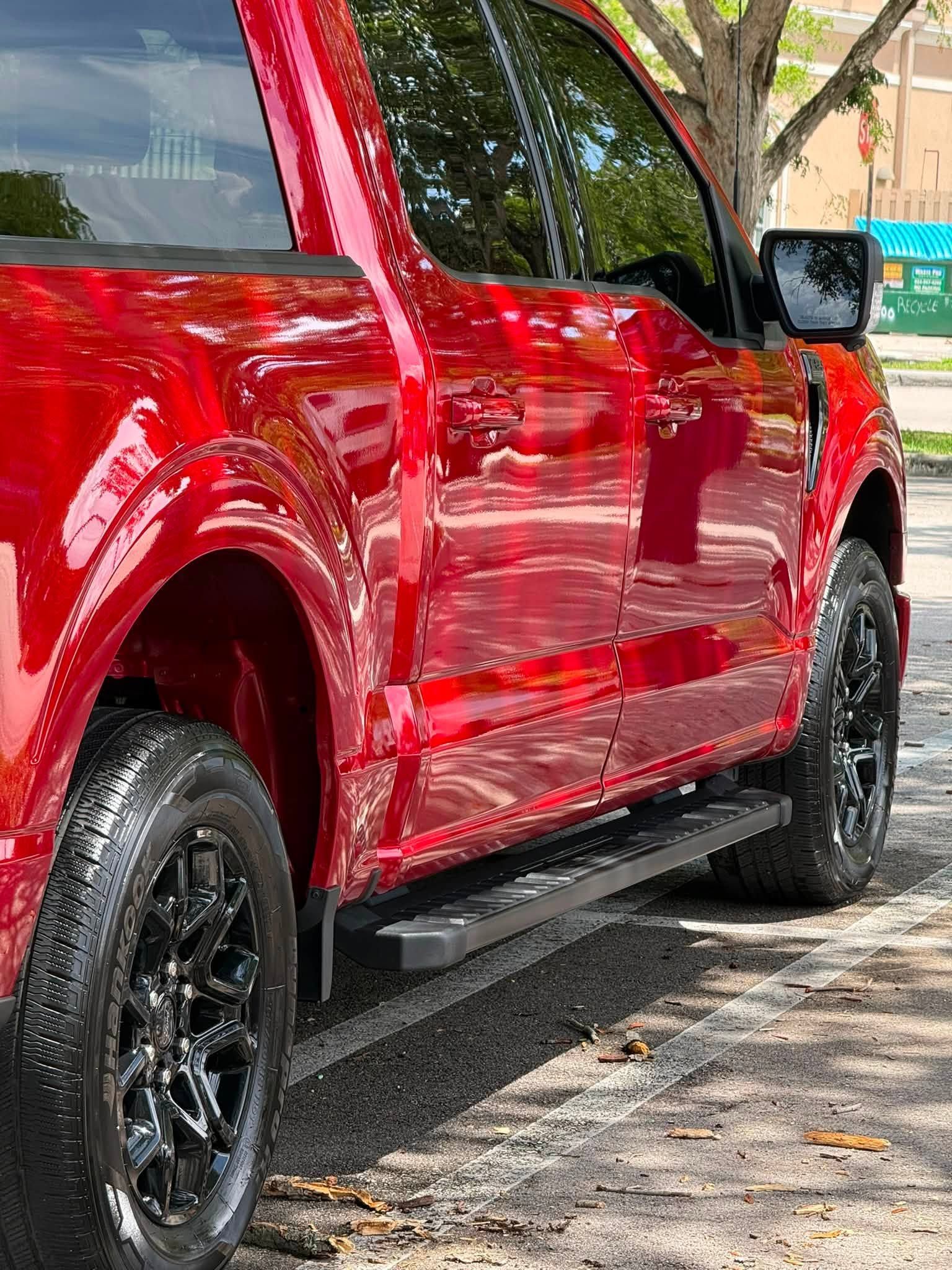 Red pickup truck parked on a street, viewed from the side.