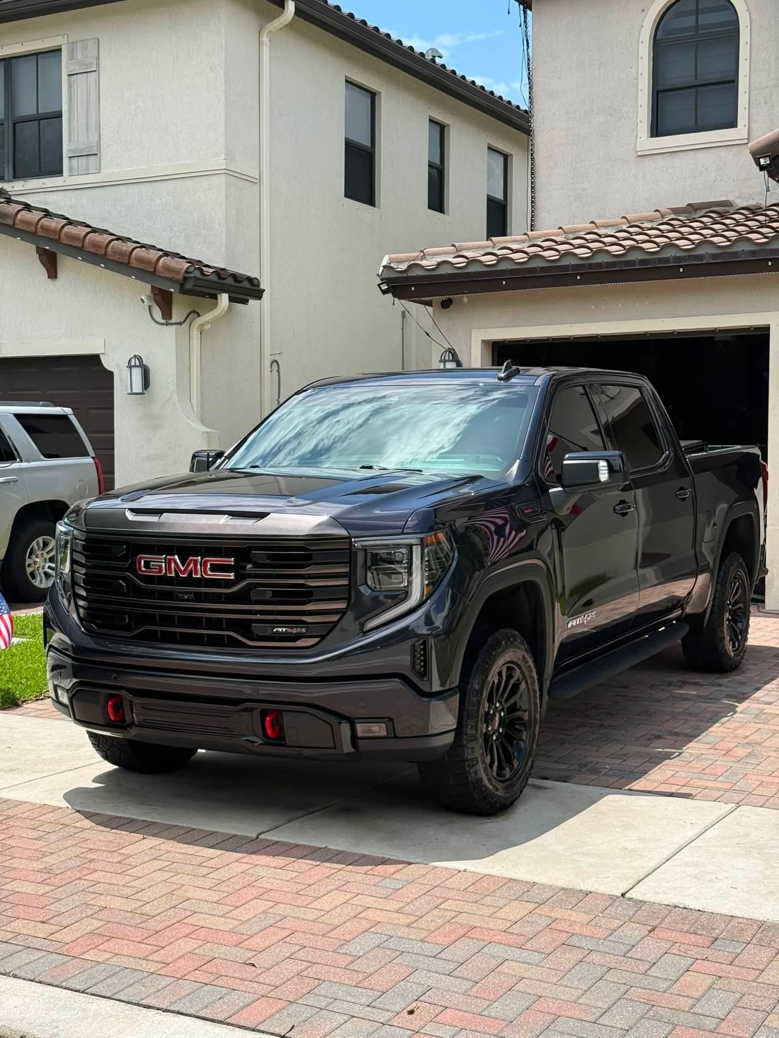 Black GMC pickup truck parked in a driveway in front of a stucco house.