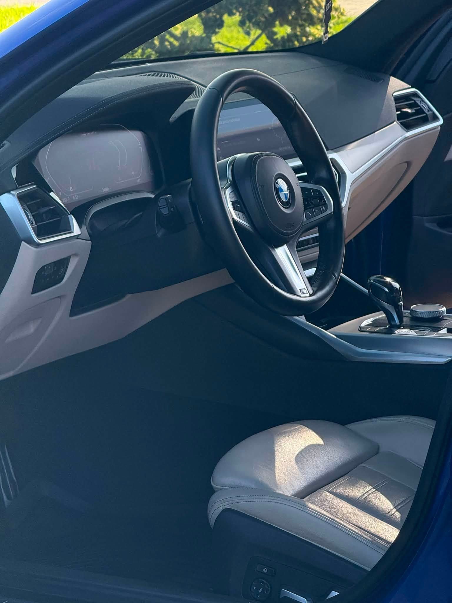 Car interior with black leather seats, steering wheel, and dashboard in bright daylight.