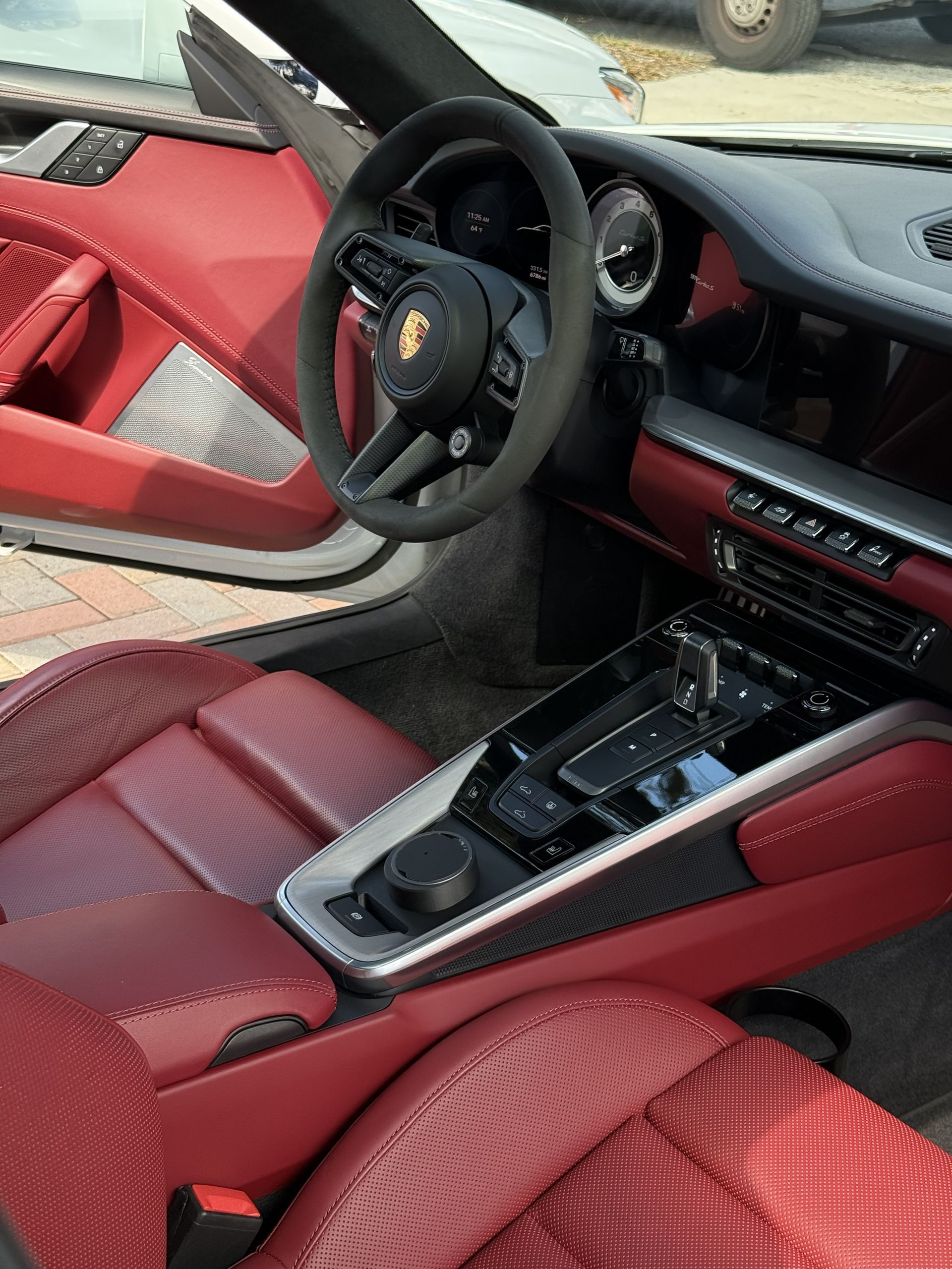Red leather Porsche interior with steering wheel, center console, and dashboard visible