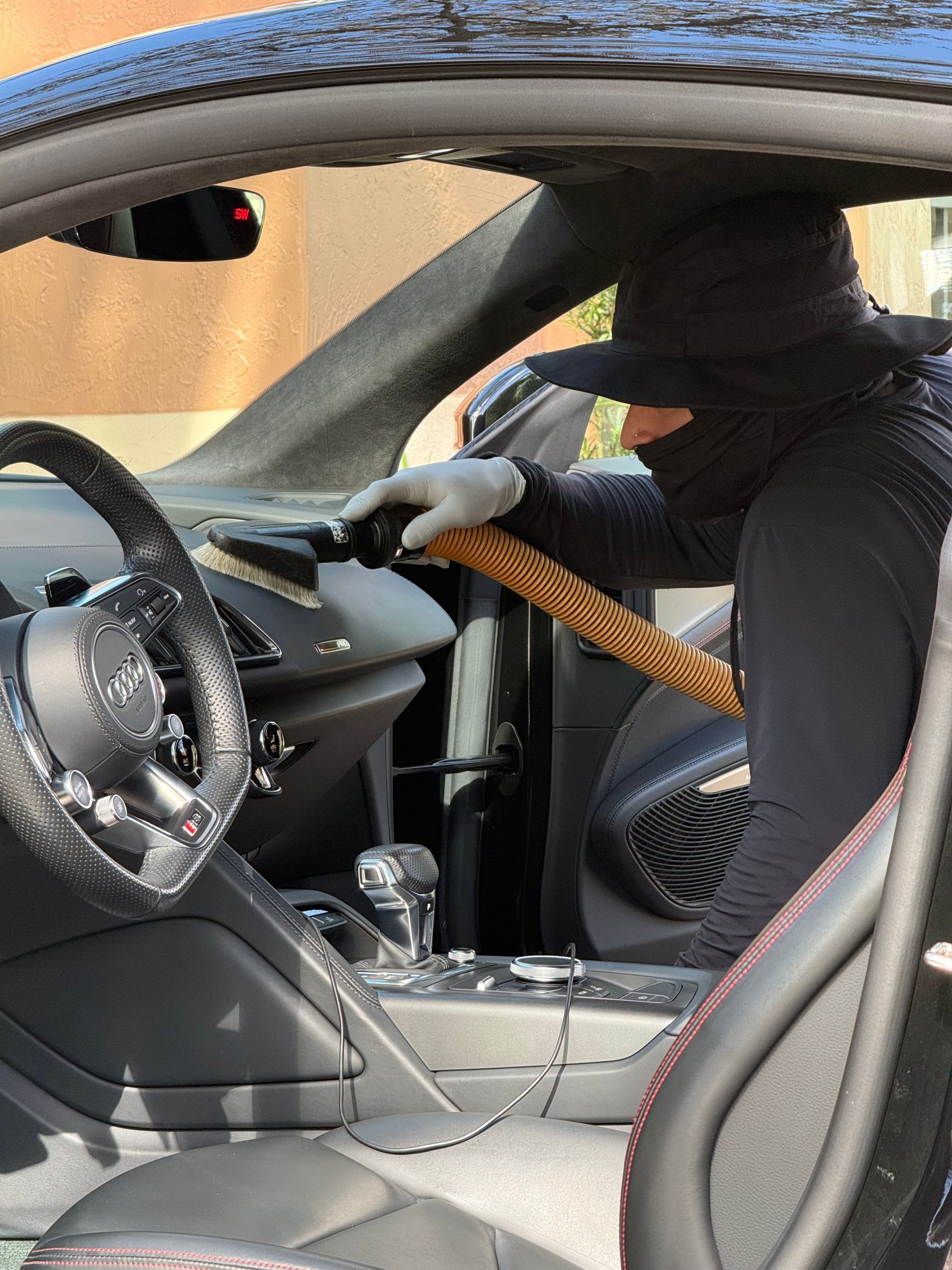 Masked person reaching into a car through the passenger window with a tool