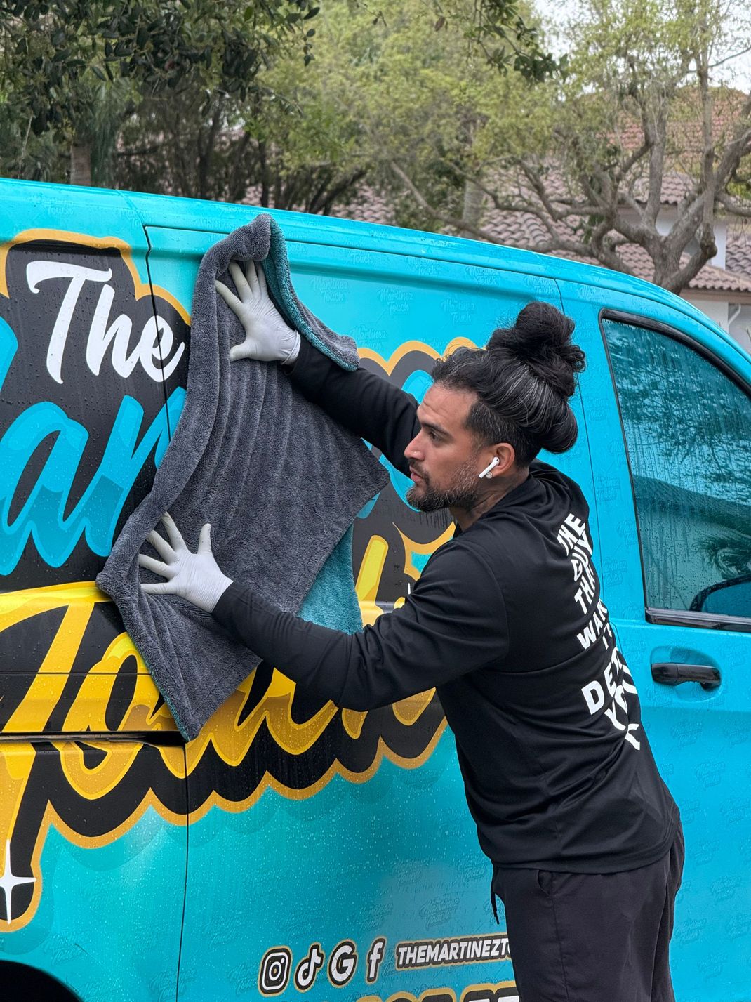 Person applying a large black decal to a colorful van outdoors
