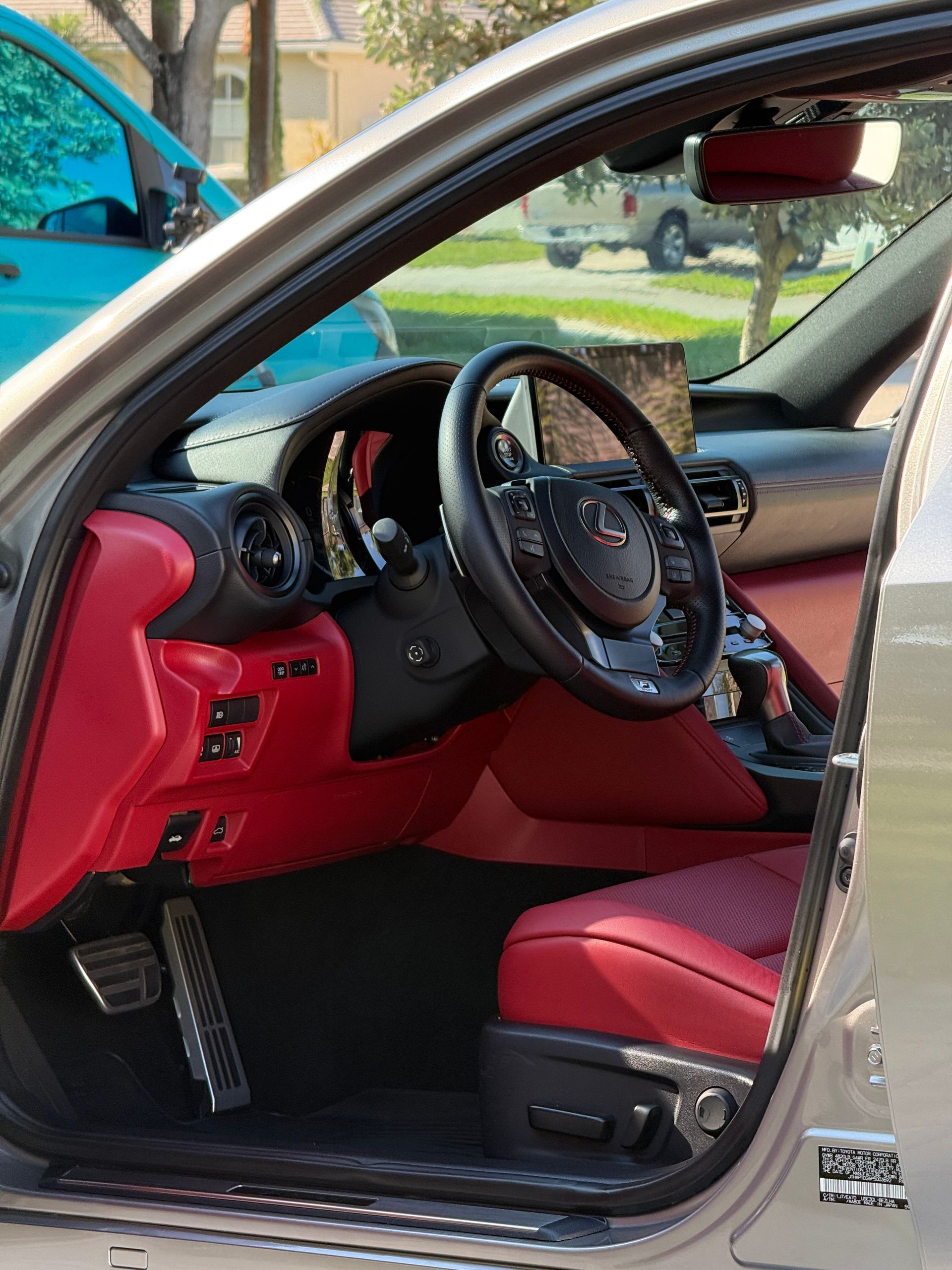 Red car interior with driver’s door open, showing black steering wheel and red leather seats.