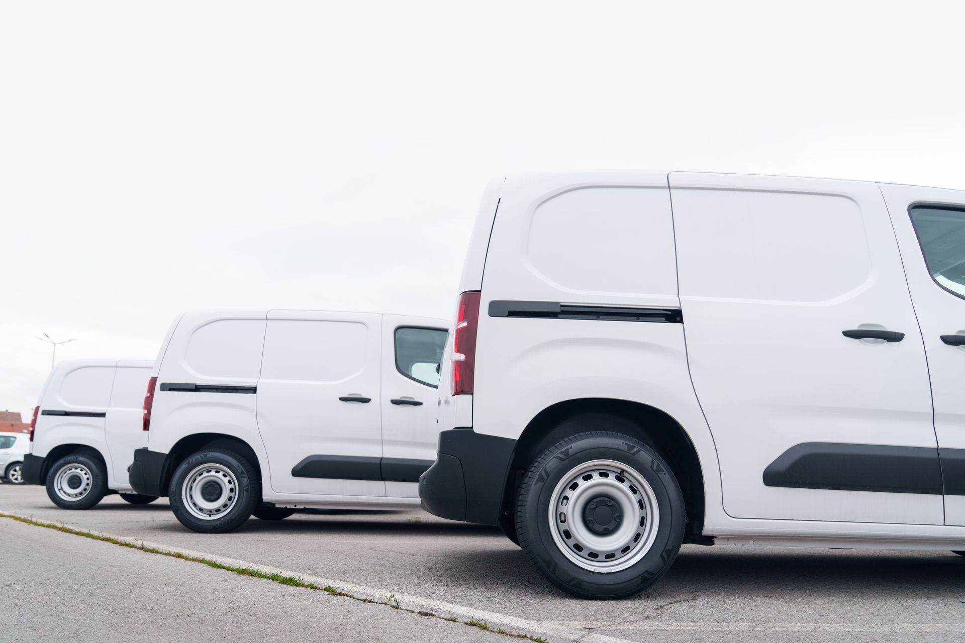Two white delivery vans parked in a lot, viewed from the side.