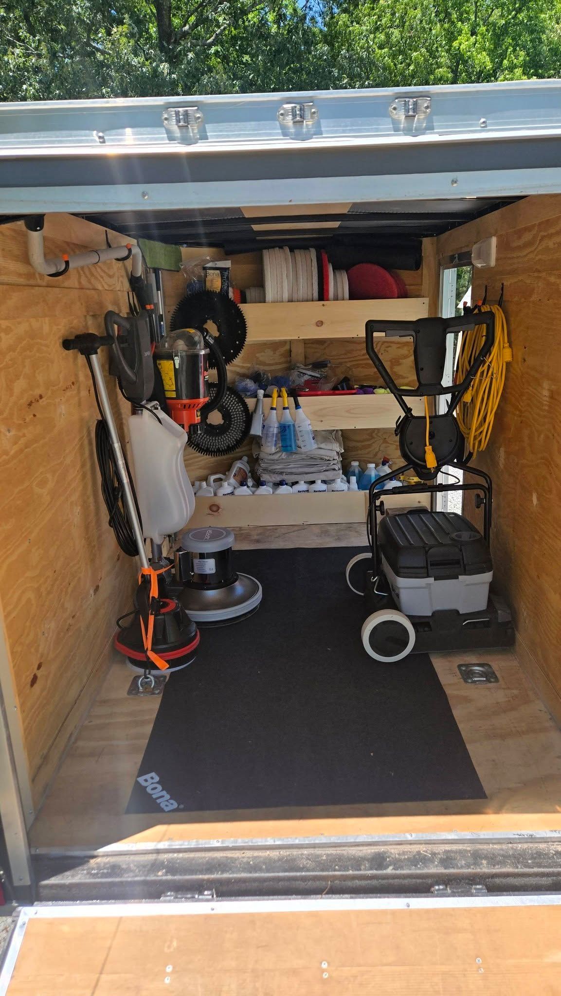 Small utility van interior with shelves, tools, and equipment on a black floor mat