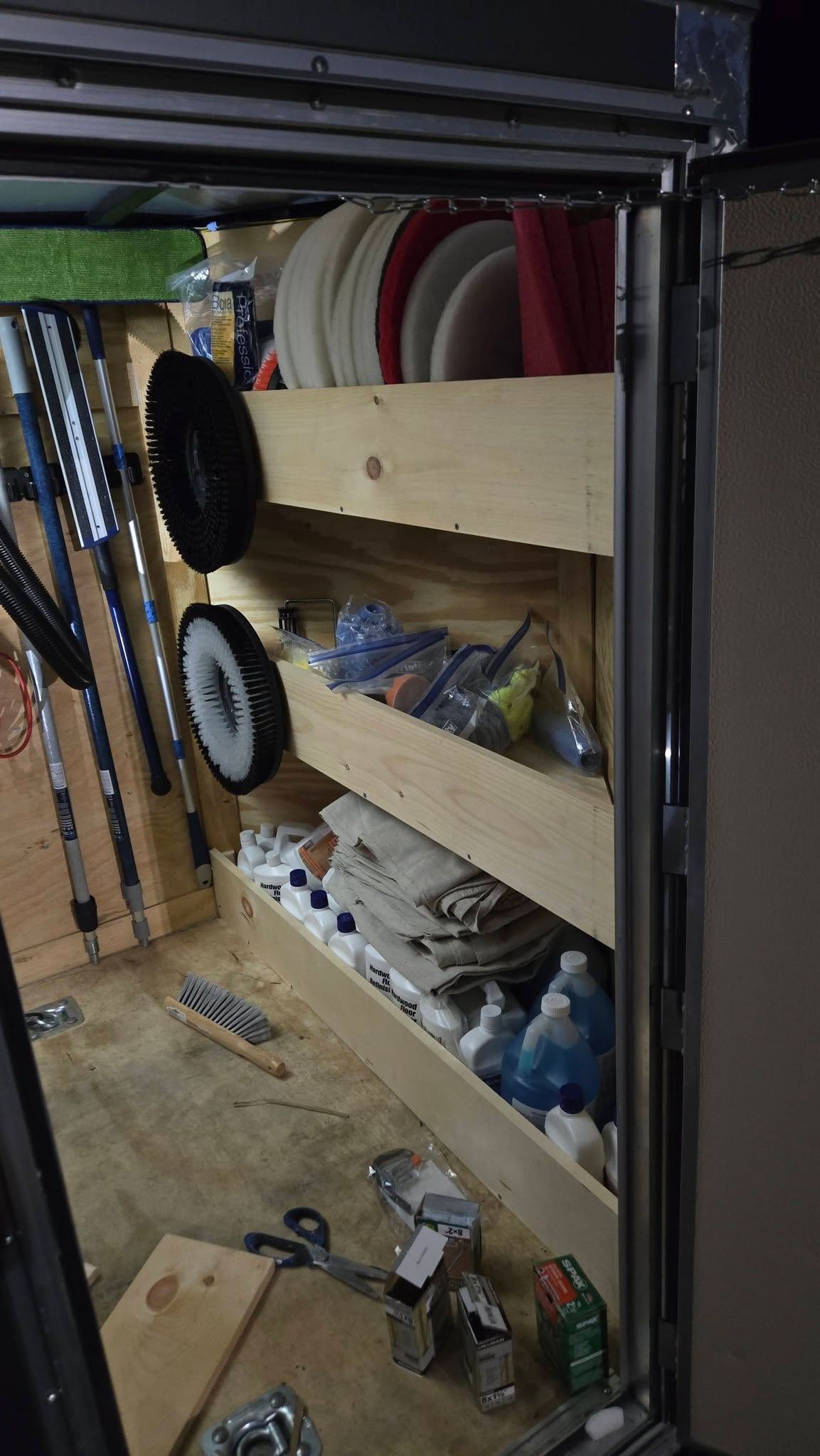 Workshop storage shelves with tools, hoses, and supplies arranged in a cluttered garage corner