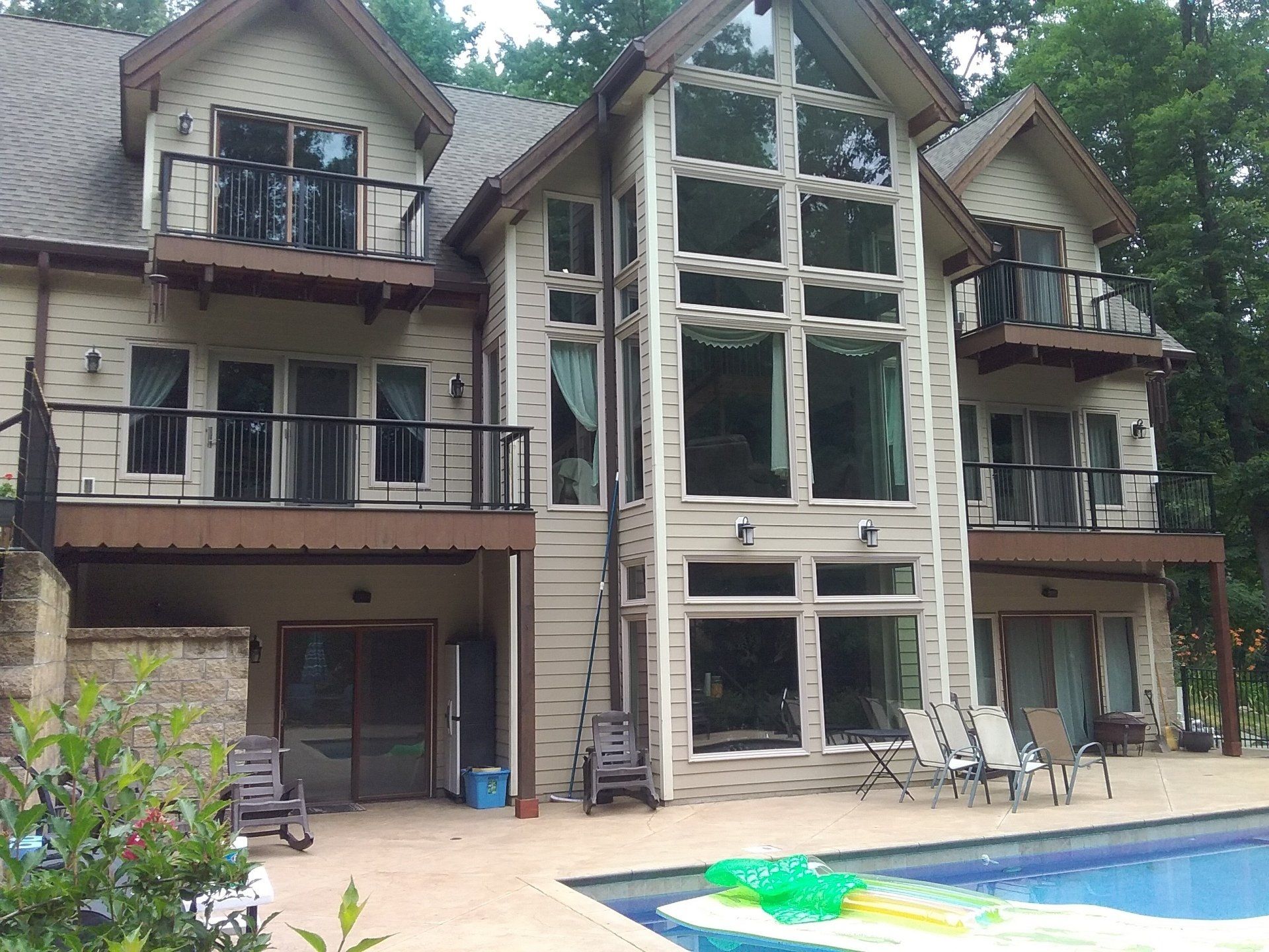 Beige house with large windows, balconies, and a swimming pool in the yard.