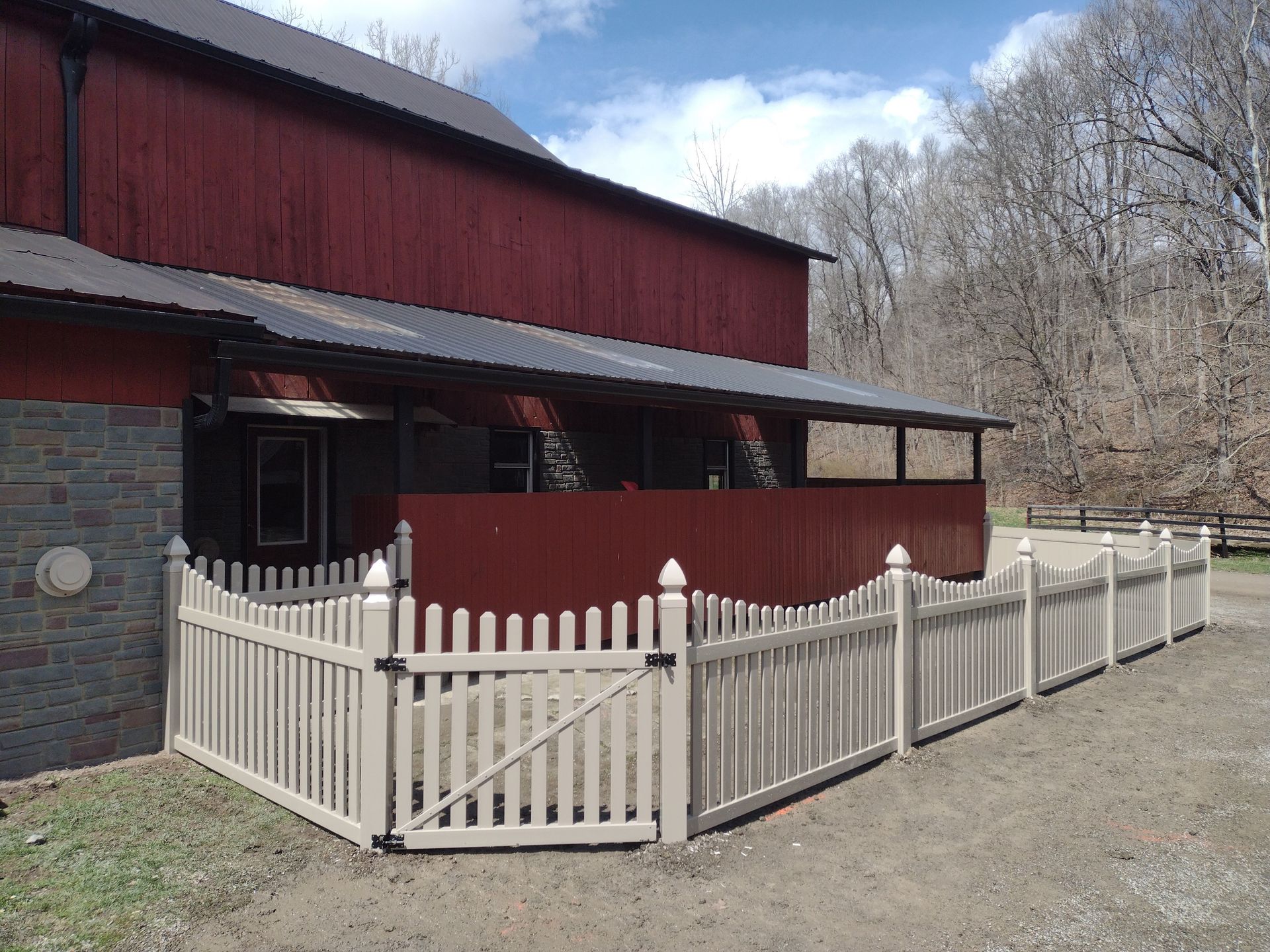 Red barn with beige picket fence.