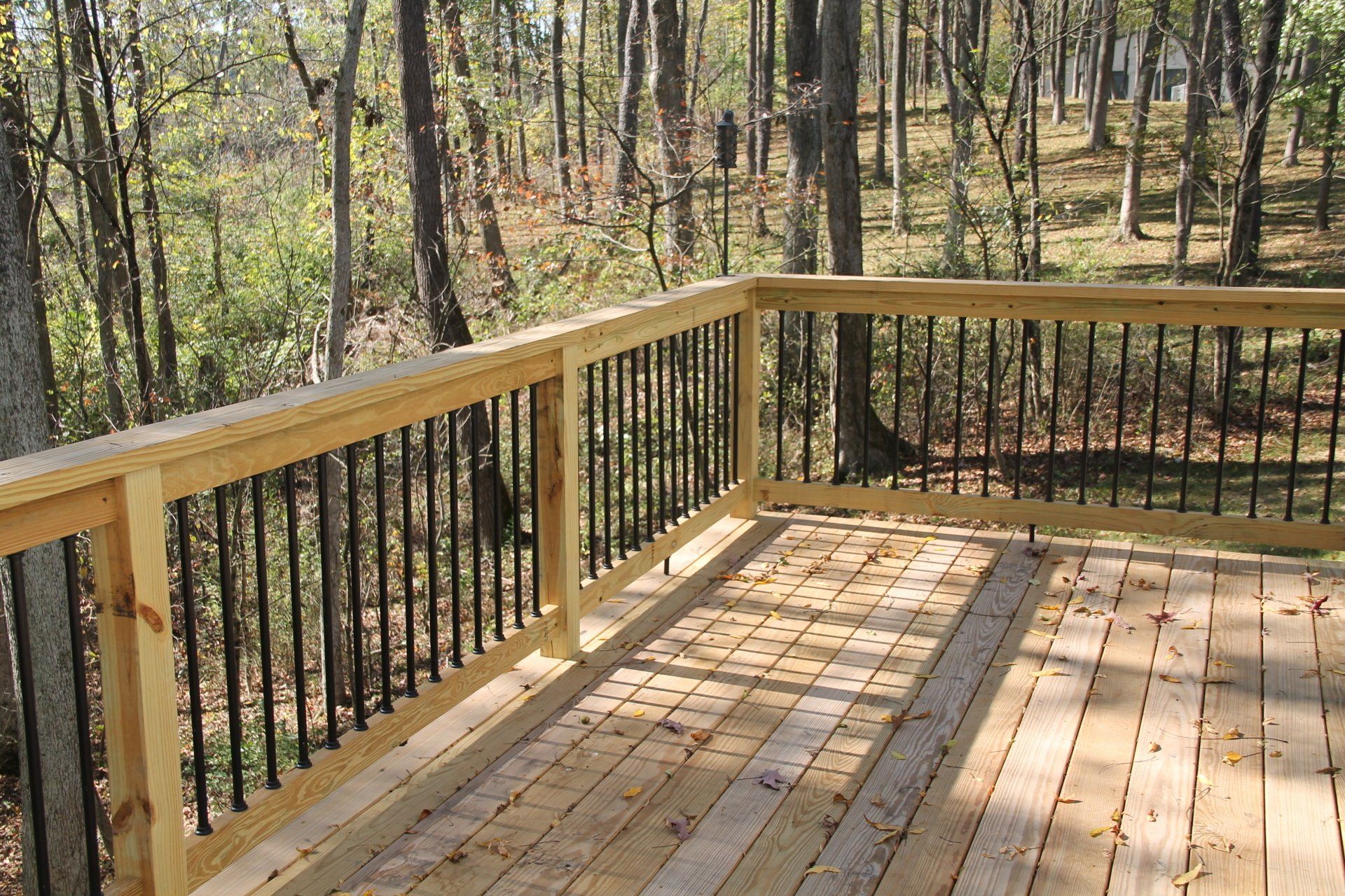 Wooden deck with black railings overlooking a forest.