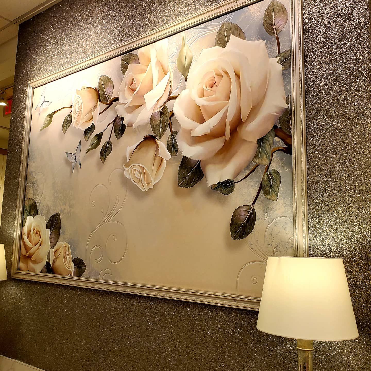 A painting of roses is hanging on a wall next to a lamp artist teen room