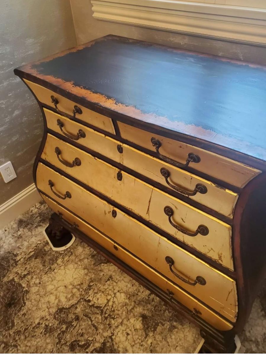A dresser with a black top is sitting on a rug in a room.