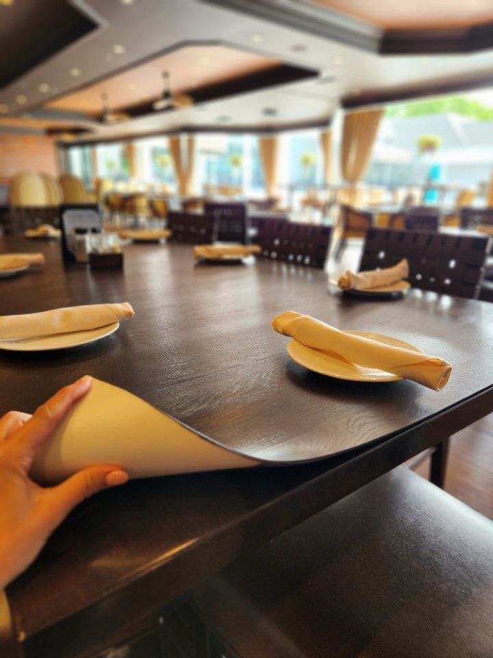 A person is holding a napkin over a table in a restaurant