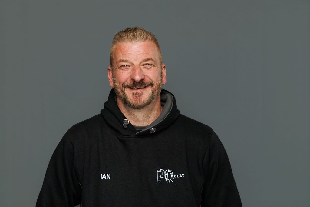 Smiling man in a black hoodie against a plain gray background