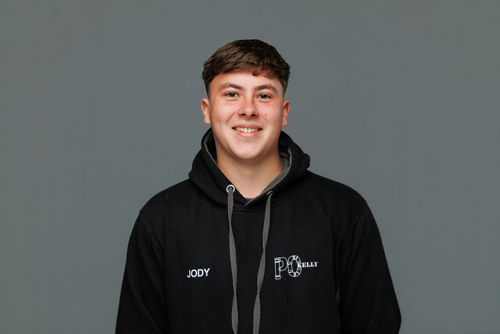 Person smiling in a black hoodie against a plain gray background