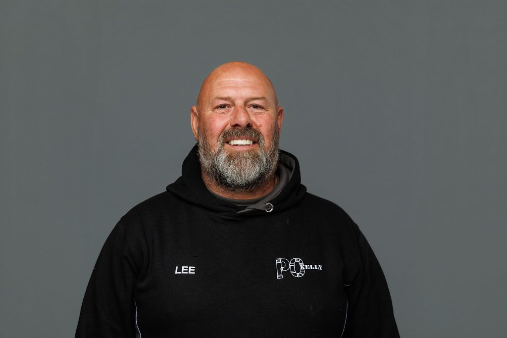 Smiling man in a black hoodie against a plain gray background