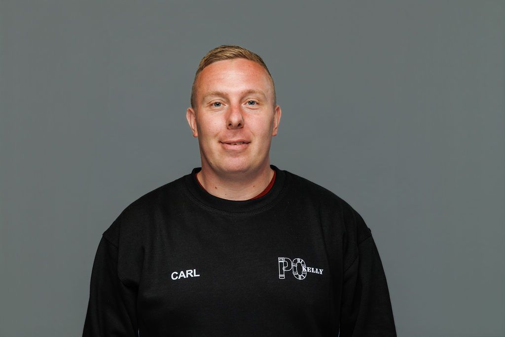 Man in a black shirt standing against a plain gray background