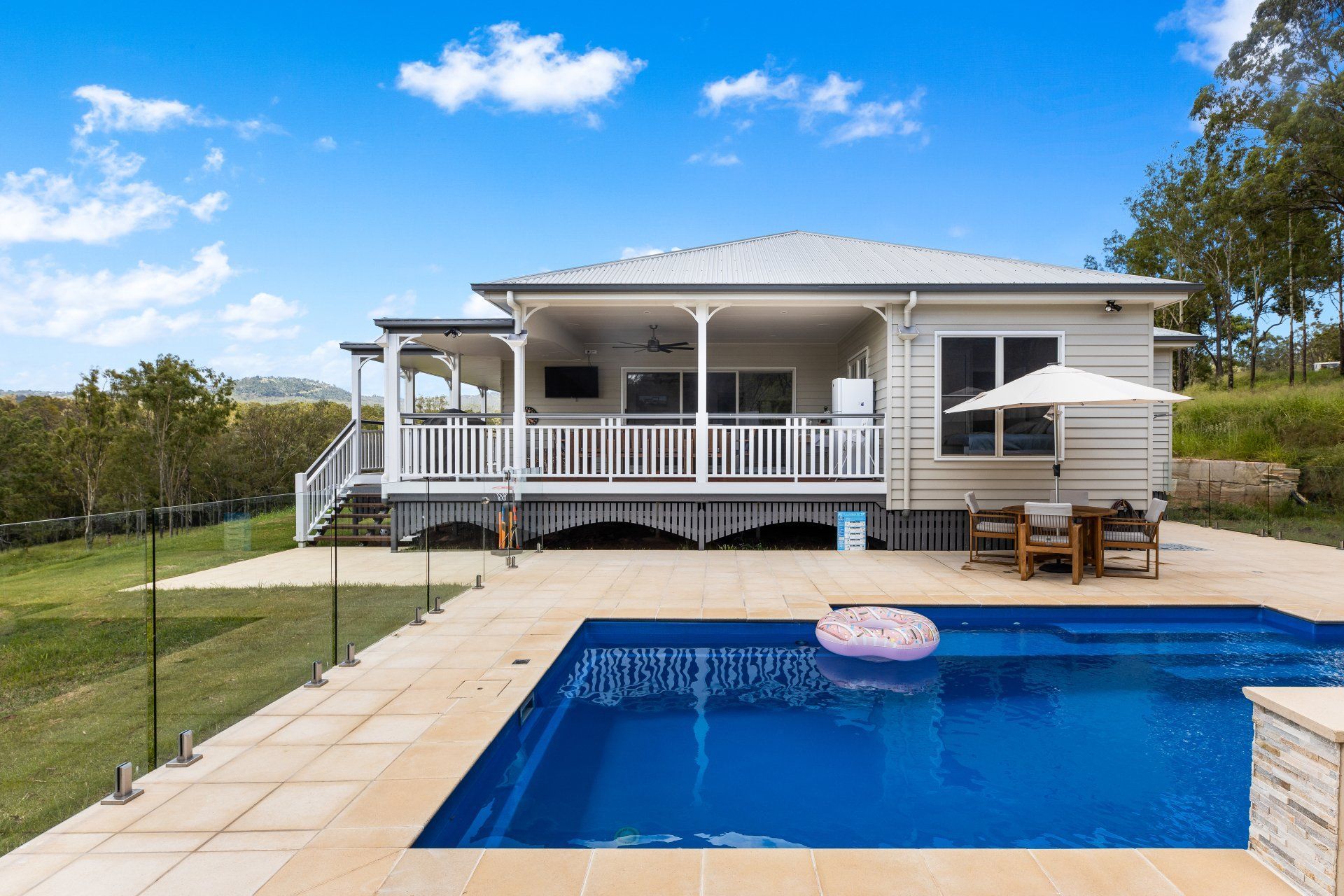 House with a pool. White house with porch, pool with floating ring, sunny day.