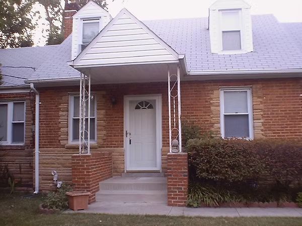 Brick house front entrance with white door, steps, small porch, and dormer windows
