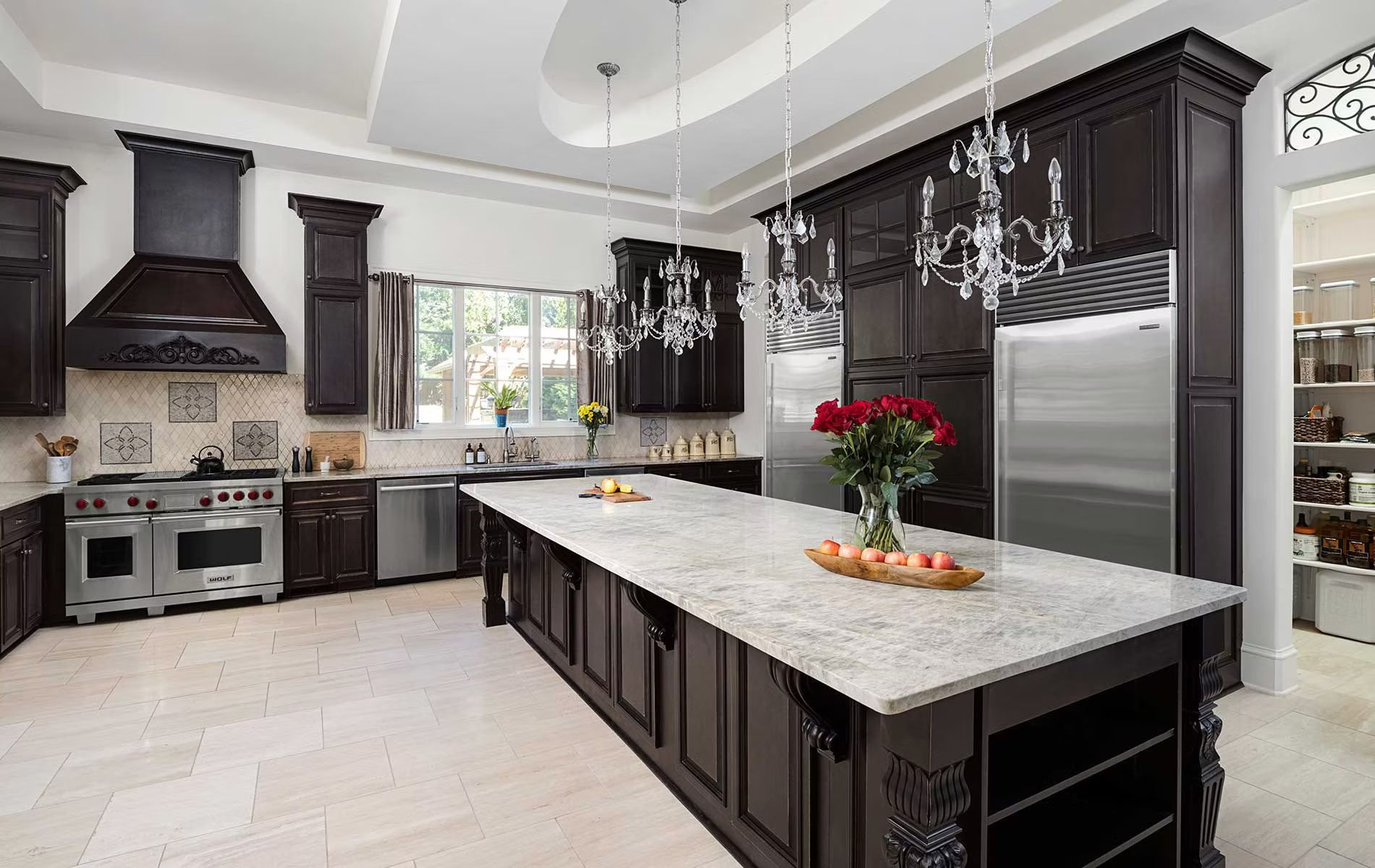 Elegant dark-wood kitchen with marble island, stainless steel appliances, and flowers on the counter