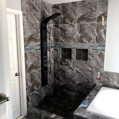 Modern bathroom with dark marble-tile walk-in shower and white tub edge