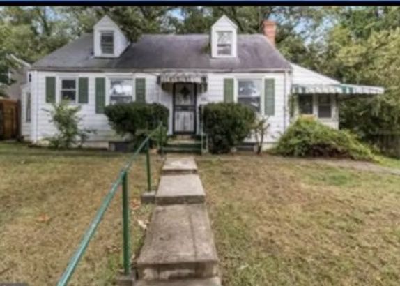 White house with a front walkway, porch, dormer windows, and a lawn in front