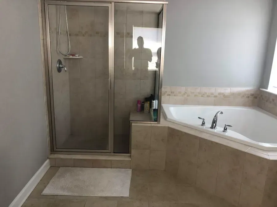 Bathroom with glass shower stall, large soaking tub, and beige tile flooring.