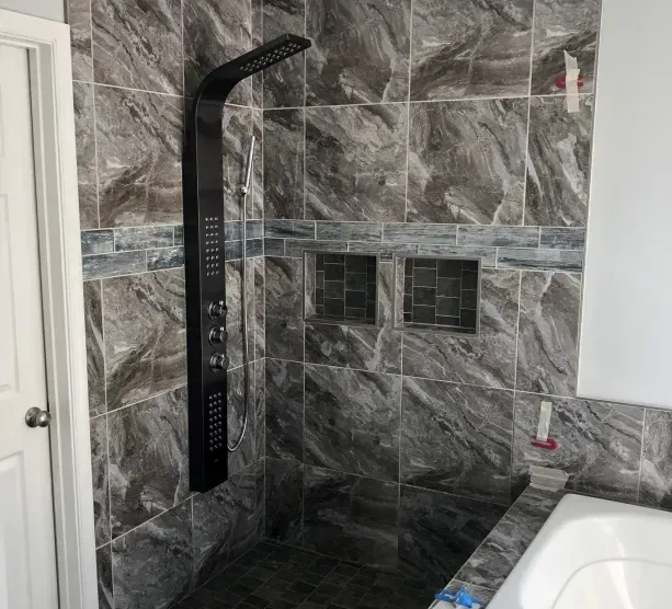 Walk-in shower with dark stone tile, black rainfall showerhead, and built-in wall niches