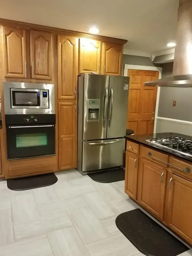Modern kitchen with wooden cabinets, stainless steel refrigerator, microwave, and gas range