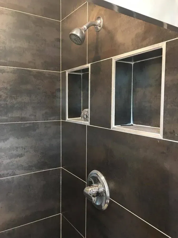 Tiled shower with chrome fixtures and two recessed soap niches