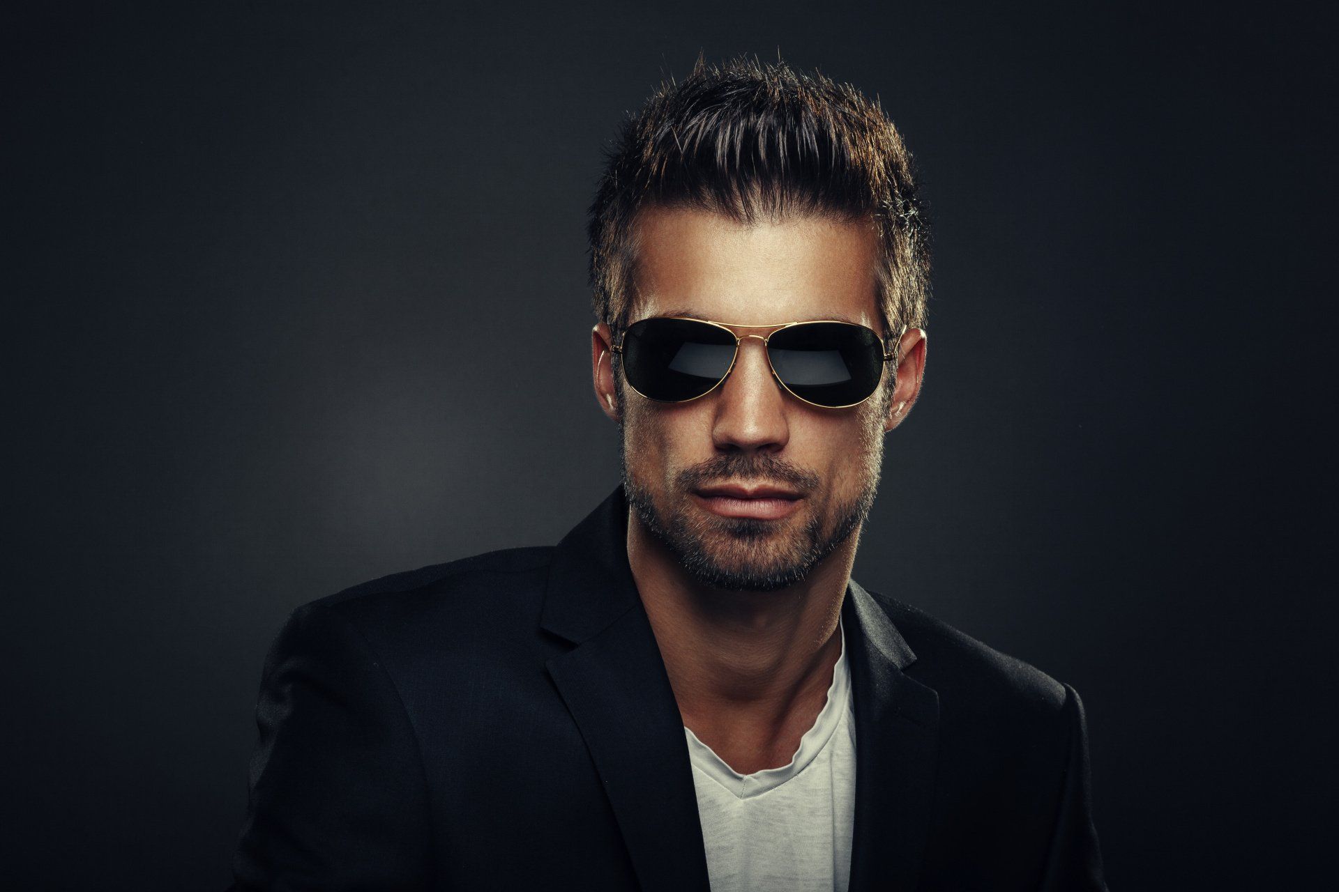 Ein Mann im Anzug und mit Sonnenbrille schaut in die Kamera.