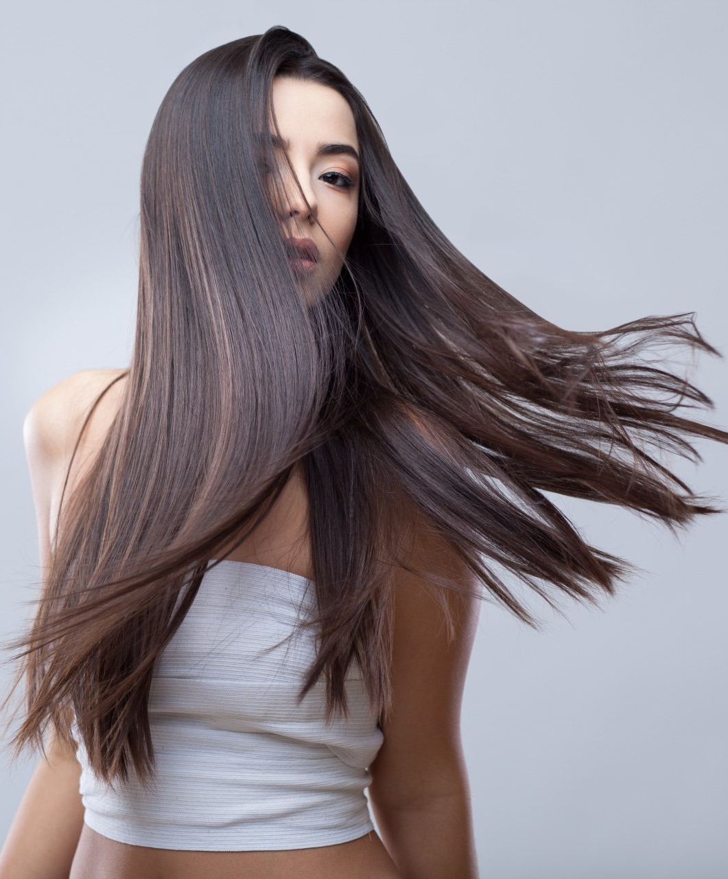 Eine Frau mit langen Haaren trägt ein weißes bauchfreies Top.
