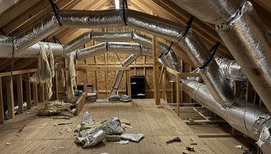 Metallic HVAC ductwork bends around a building corner, supported by brackets.