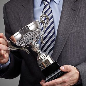 Man in suit holding a silver trophy.