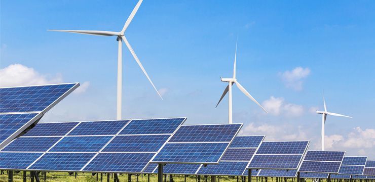 Solar panels in a field with wind turbines, under a blue sky.