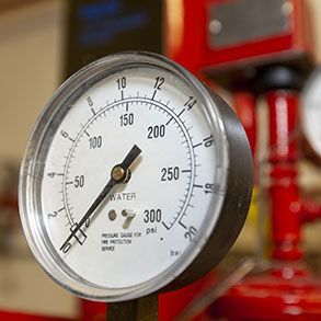 Pressure gauge, white face with black markings, reads approximately 120, connected to red pipes.