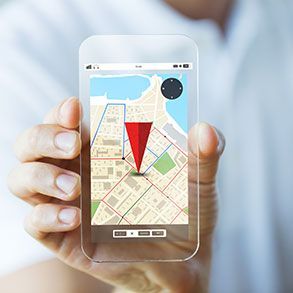 Hand holding a transparent phone displaying a map with a red location marker.