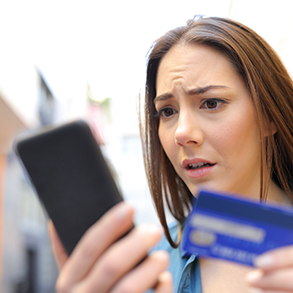 Woman looking concerned at her phone and a blue credit card.
