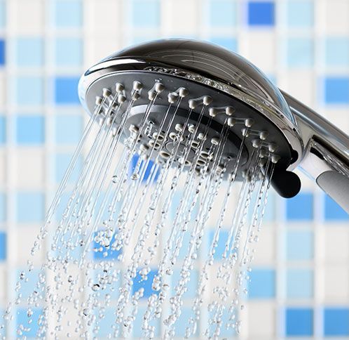 Chrome shower head spraying water, blue and white tiled background.