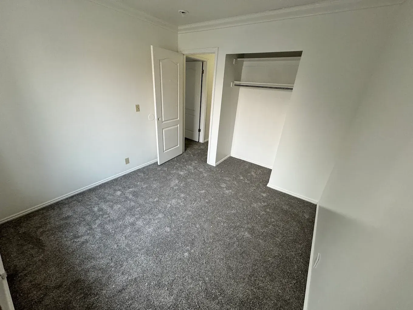 Empty white bedroom with gray carpet and open closet door