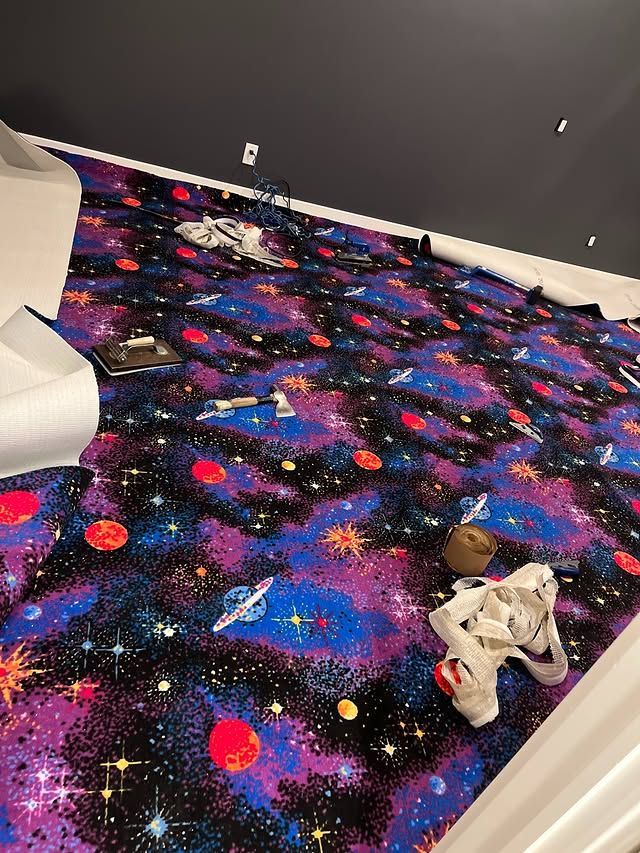 Playroom with black galaxy-pattern carpet and scattered toys near a white chair