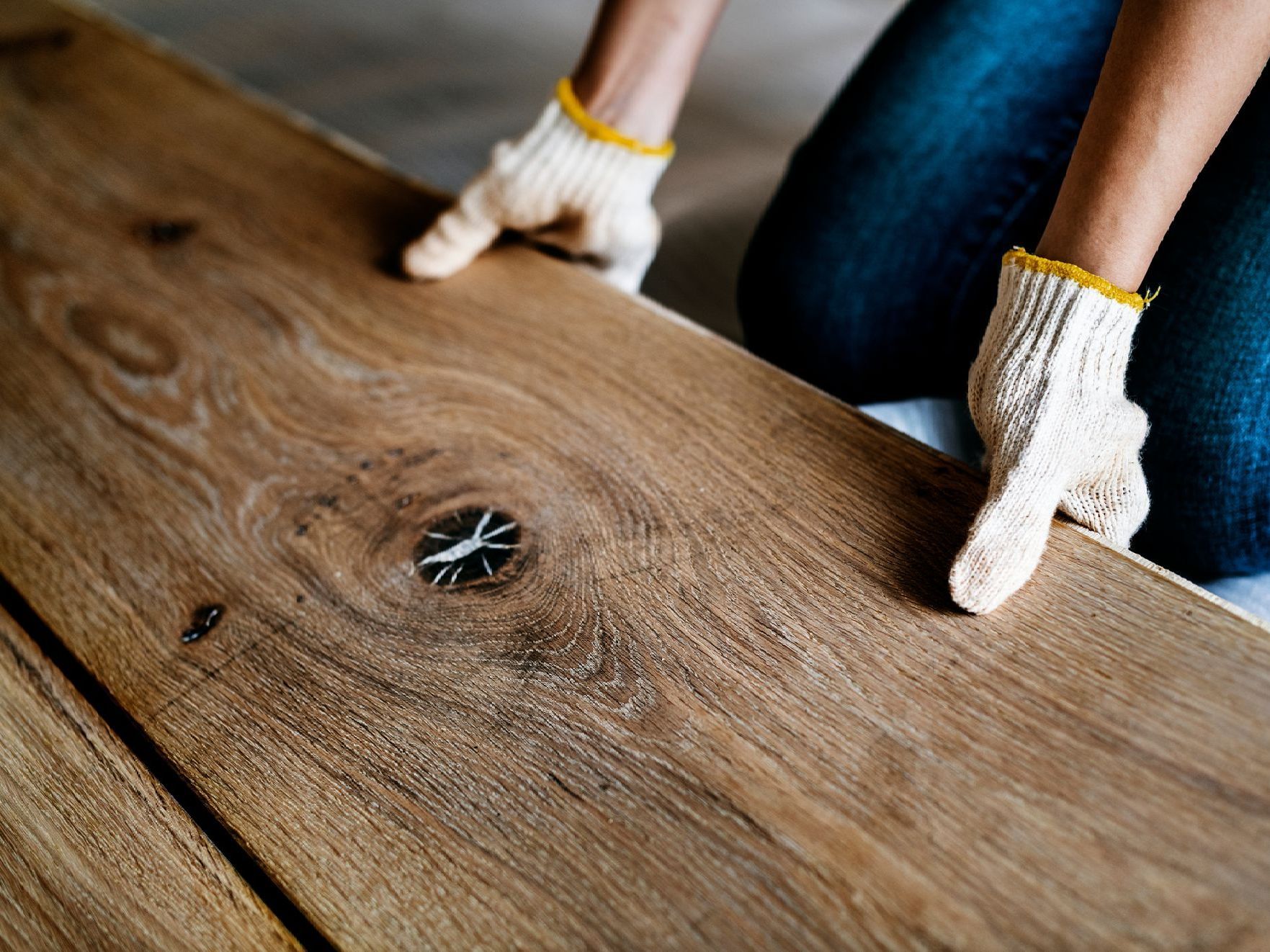 Gloved hands installing a metal drain in a wooden tabletop