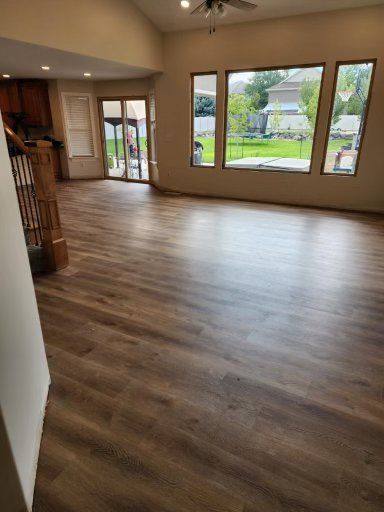 Empty living room with wood floors and large windows overlooking a green yard