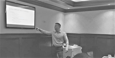Presenter pointing at a projected slide in a conference room